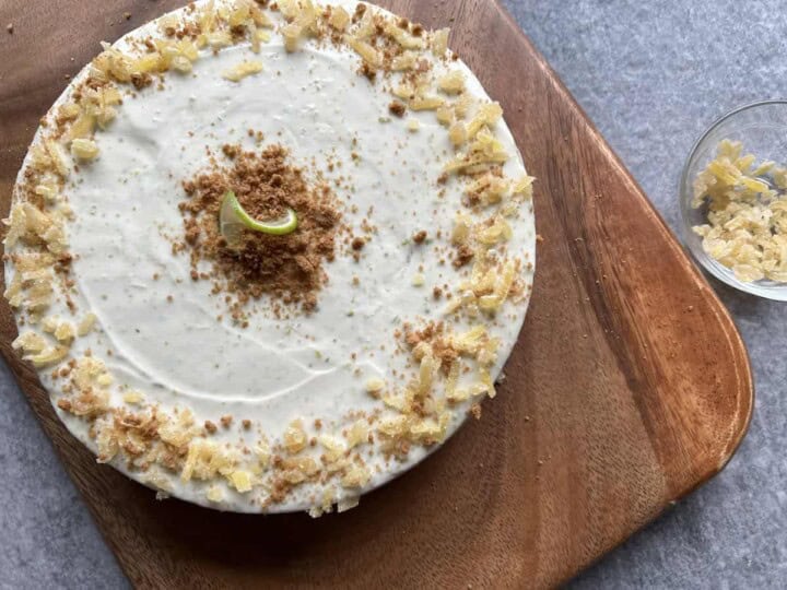 key lime cheesecake on a wooden cutting board next to a small bowl of crystallized ginger