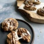 two peanut butter smores cookies on a dark matte plate. one of the cookies is partially split, showing off the gooey texture of the marshmallow as it pulls apart.