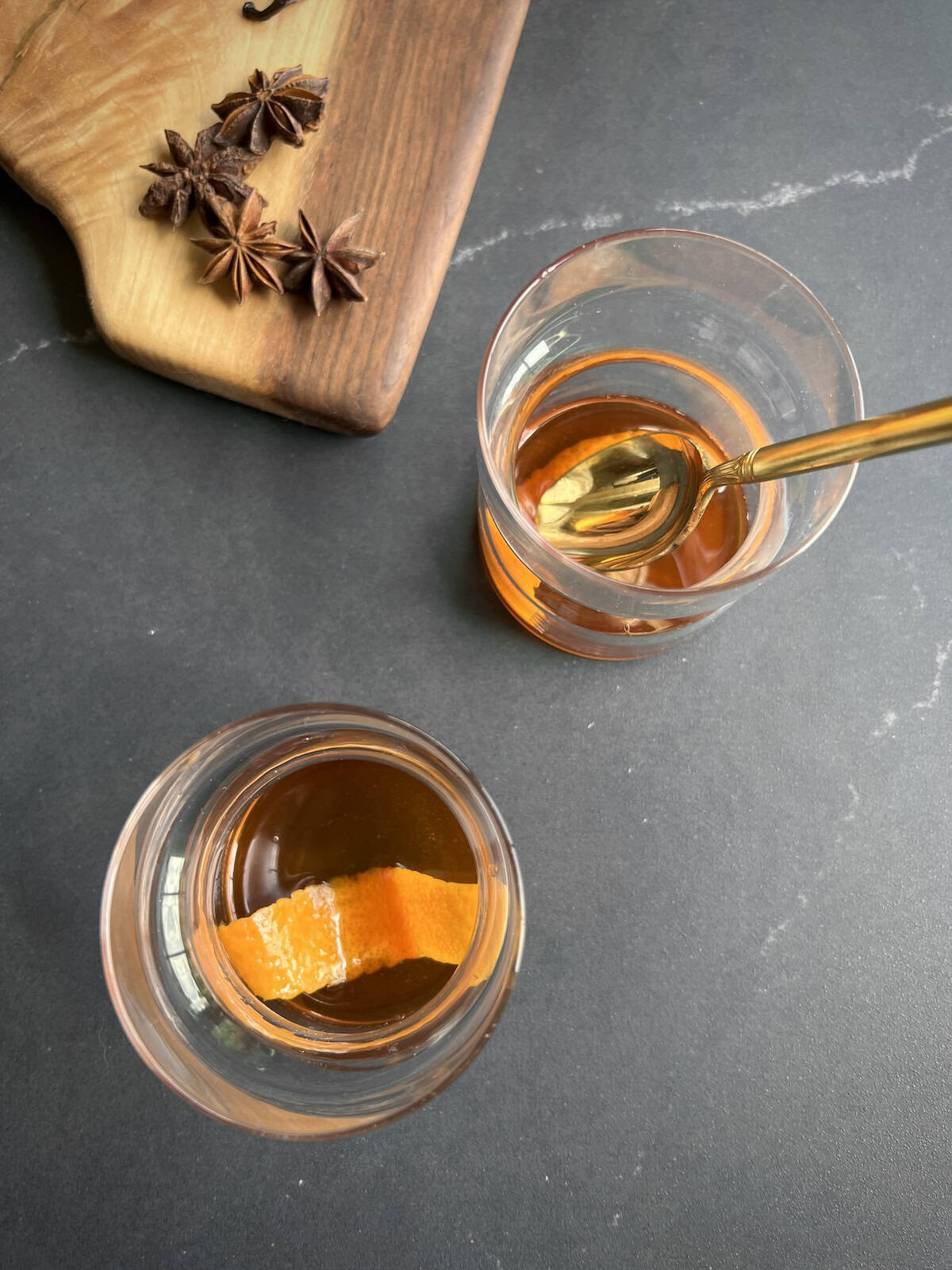 chai syrup, orange peel, and bitters are muddled in the bottom of 2 wide glasses