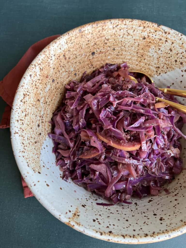 sauteed red cabbage is piled high in a large, rustic pottery-style bowl