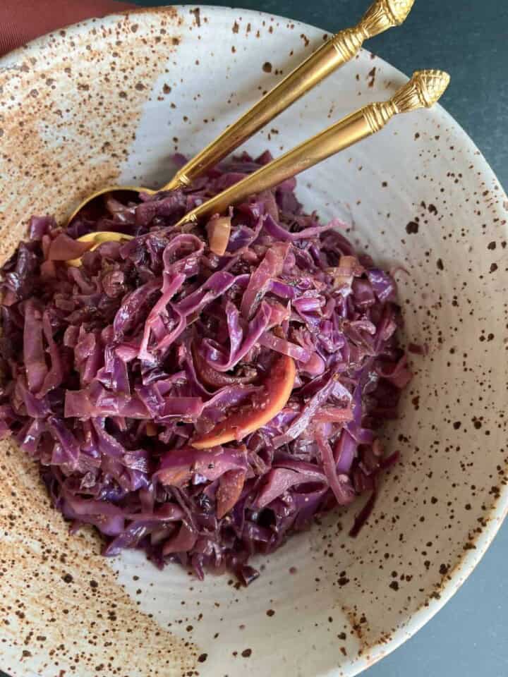 sauteed red cabbage has a brilliant purple-red coloring, with visible caraway seeds and sliced apple.