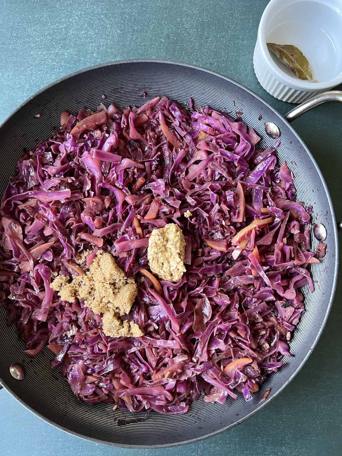 the bay leaf is remove from the skillet and mustard and brown sugar are added to the cabbage mixture
