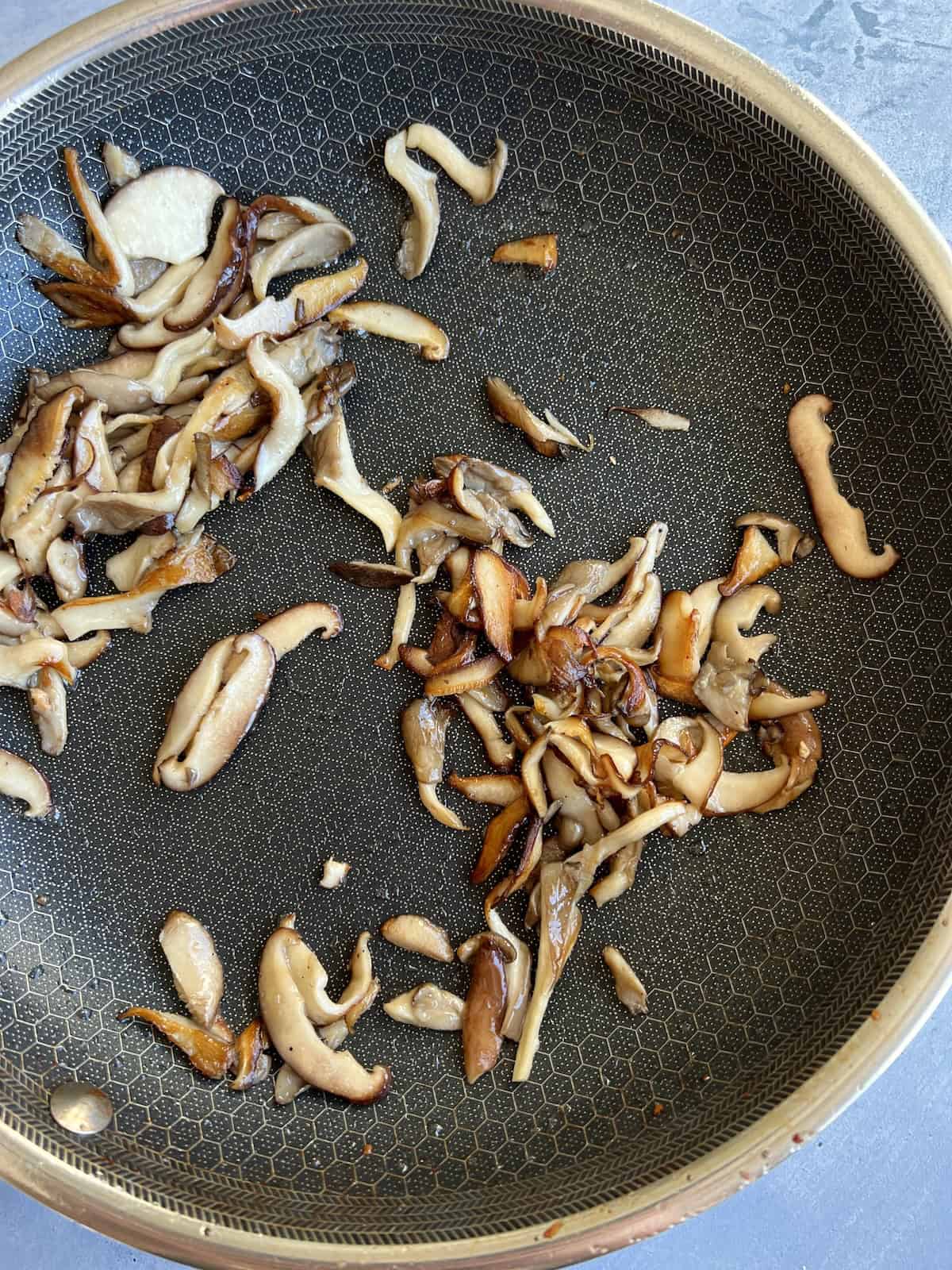 the partially cooked mushrooms have reduced in size and taken on a golden brown coloring.
