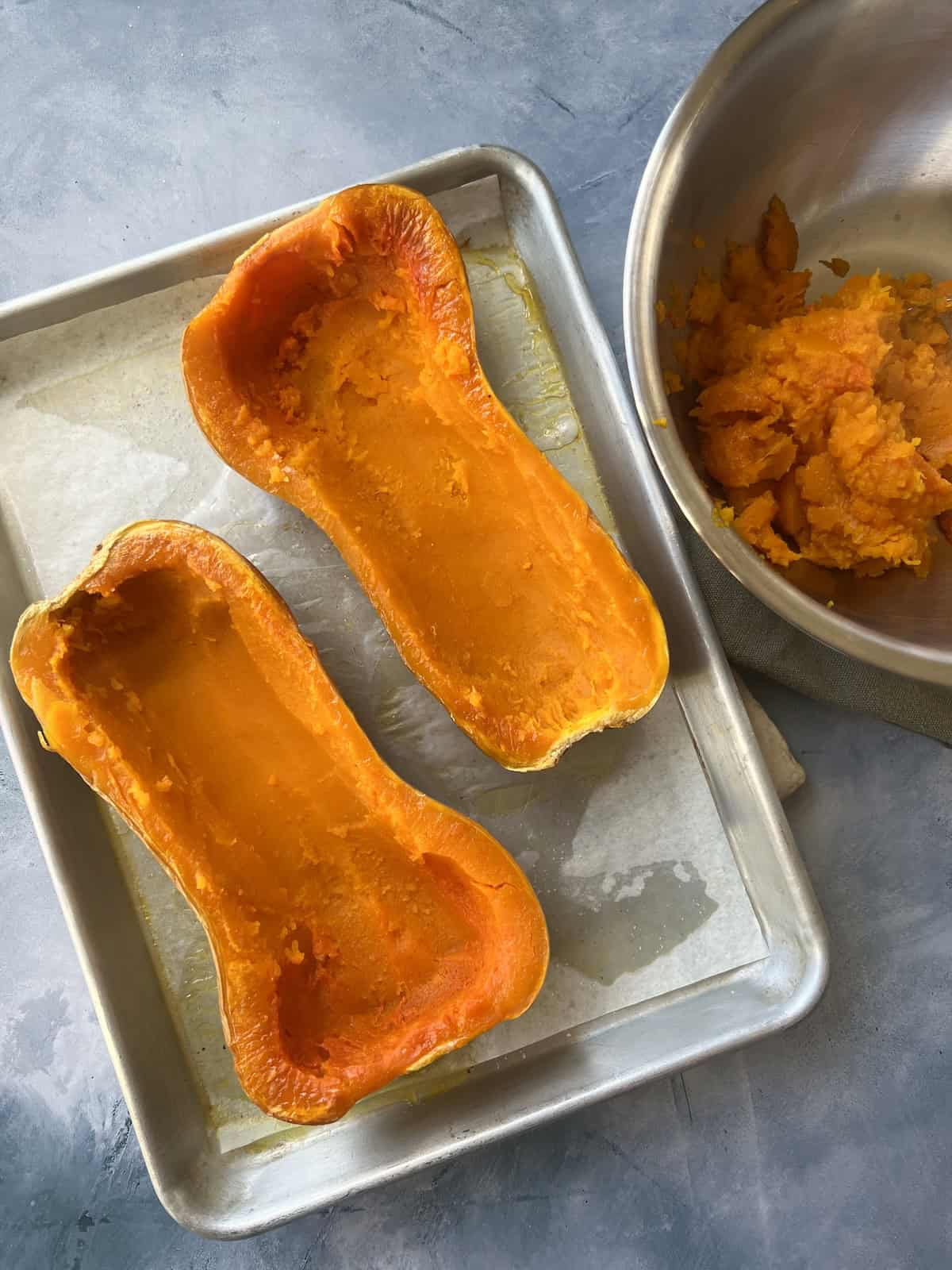 some of the squash flesh has been scraped out of each half, leaving a cavity that is about the same width and depth from top to bottom.