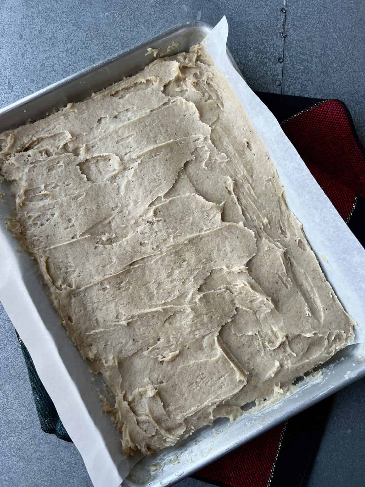 the eggnog cookie bar dough has been smoothed into an even layer in the baking sheet