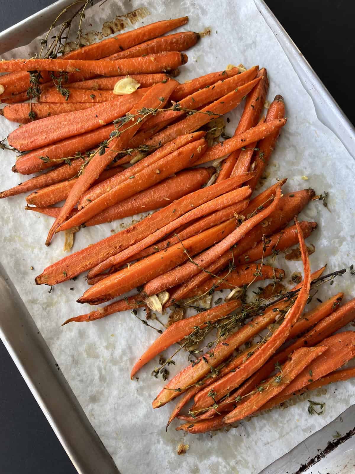 the roasted carrots are removed from the oven, showcasing their bubbly skins and lightly golden brown edges