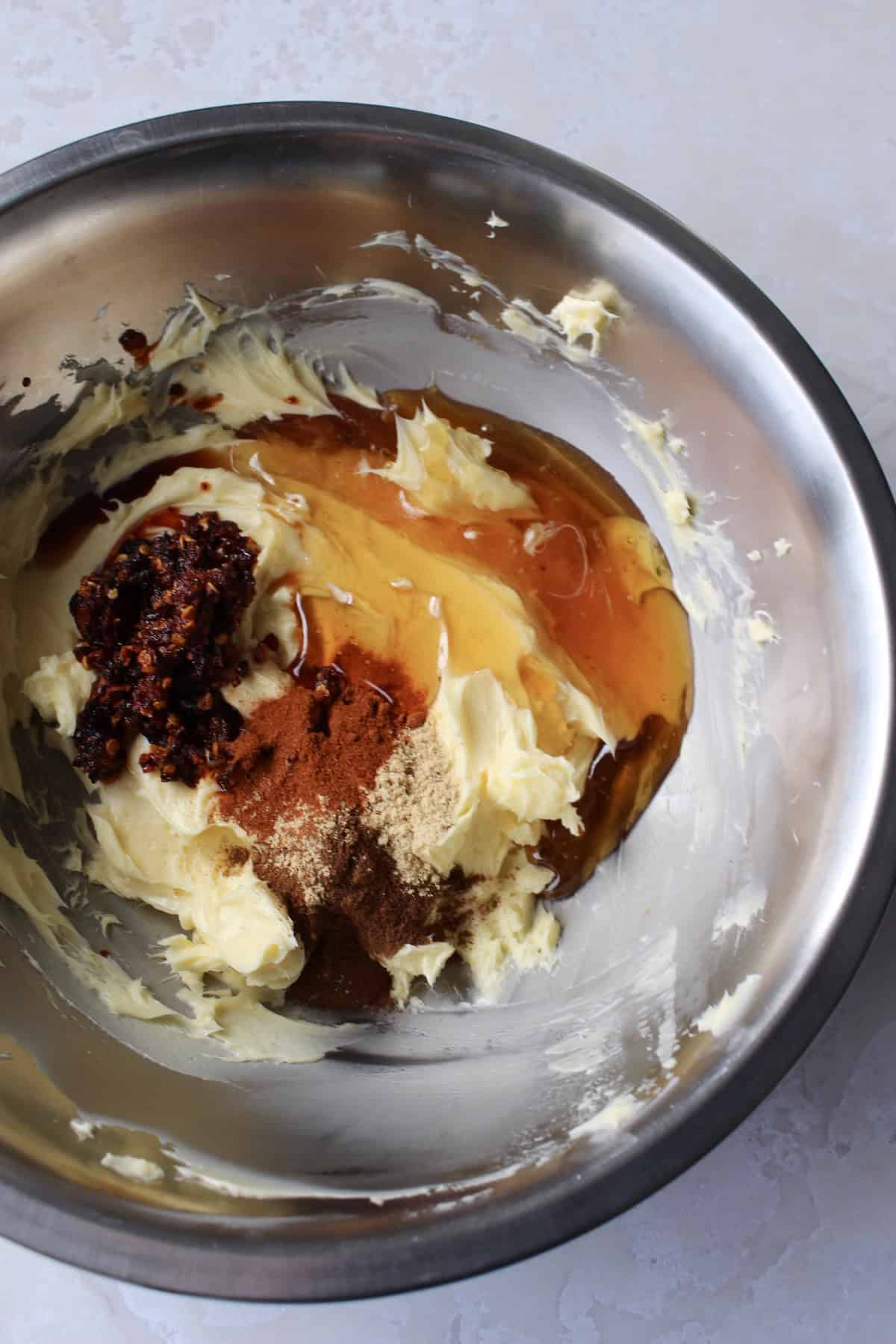 honey, vanilla, and spices are added to the bowl with the whipped butter