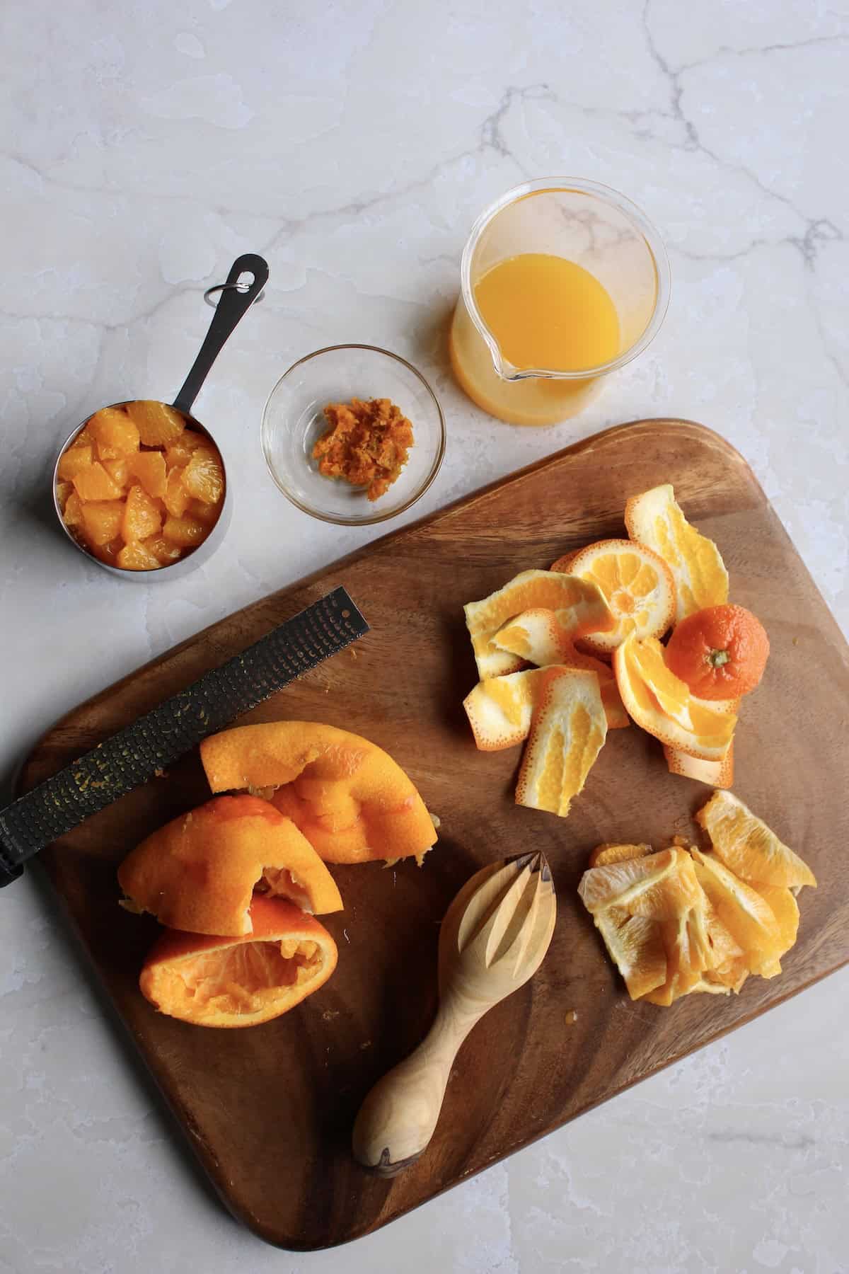 oranges in various stages of preparation on a wooden cutting board
