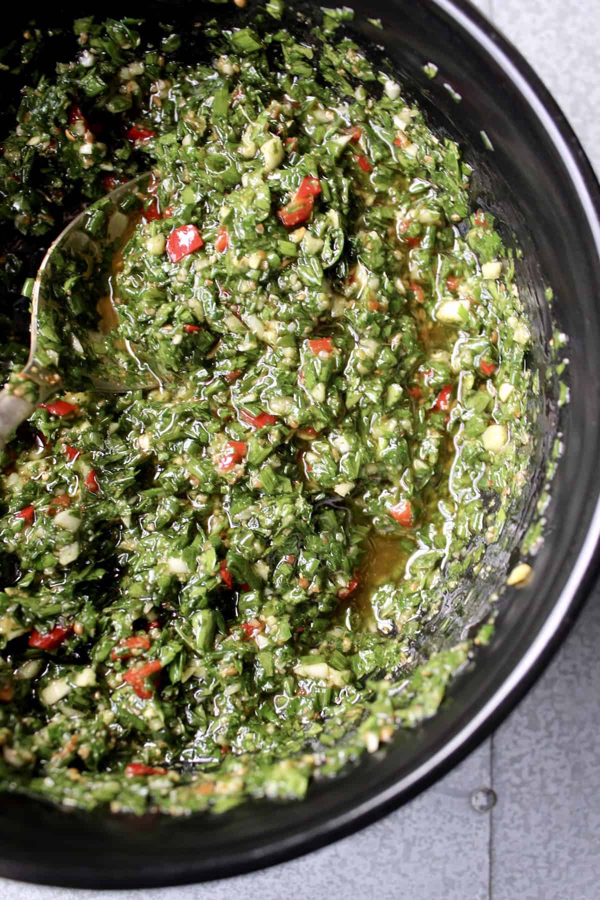 the chimichurri is stirred together, creating a loose sauce with visible bits of herbs, chili, and garlic. 