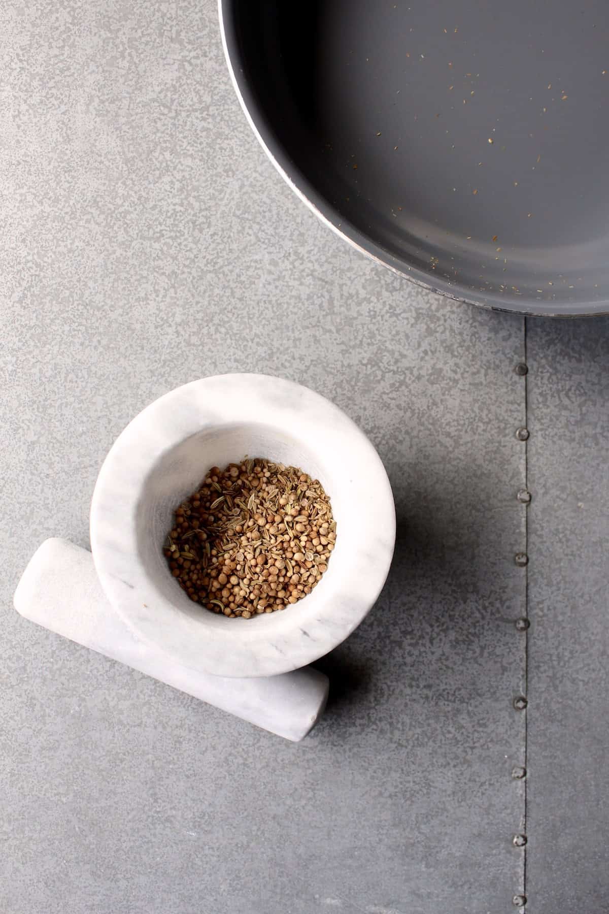 the toasted whole spices are poured into a stone mortar and pestle
