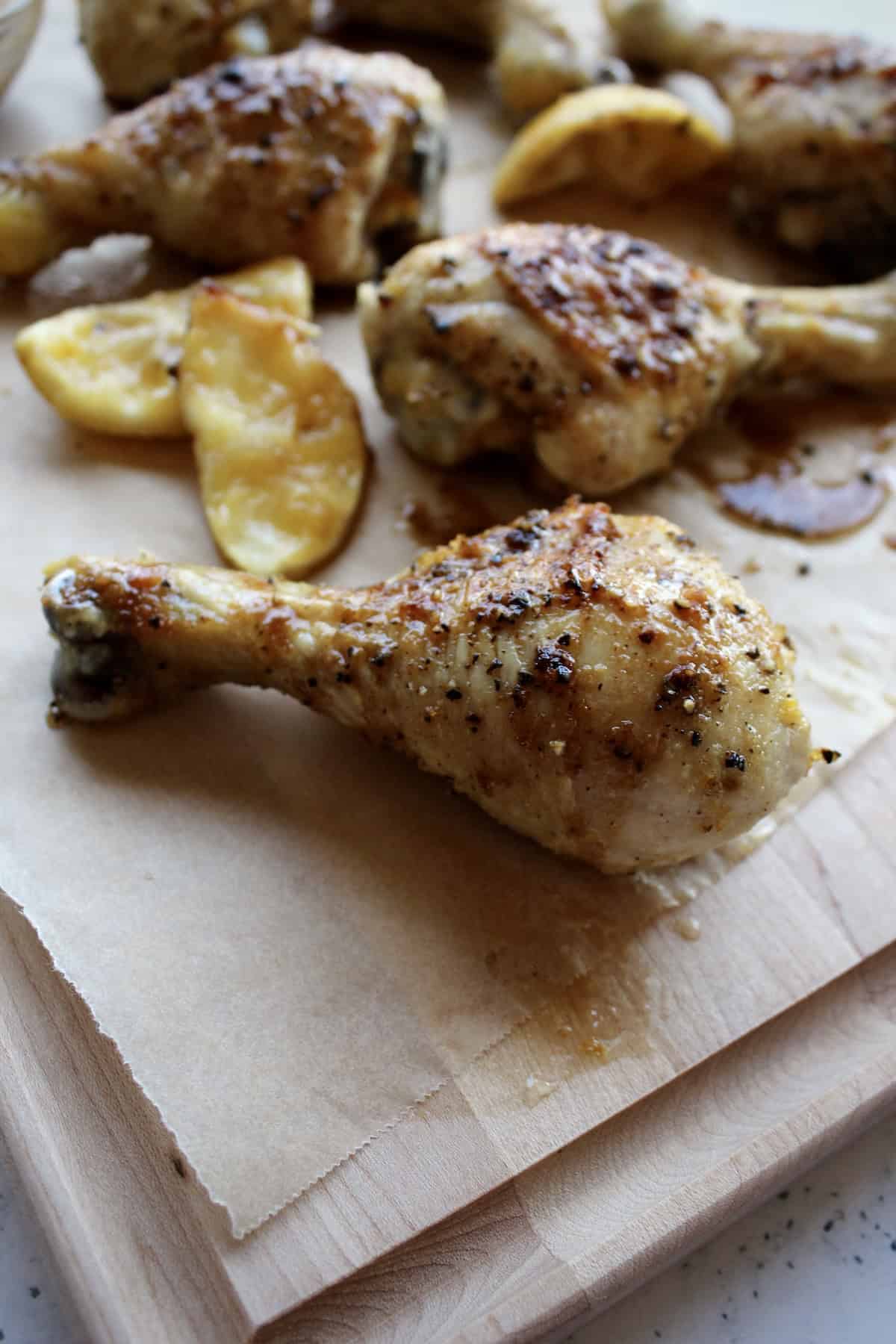 a lemon pepper chicken leg has a glossy coating of sauce and crispy golden skin