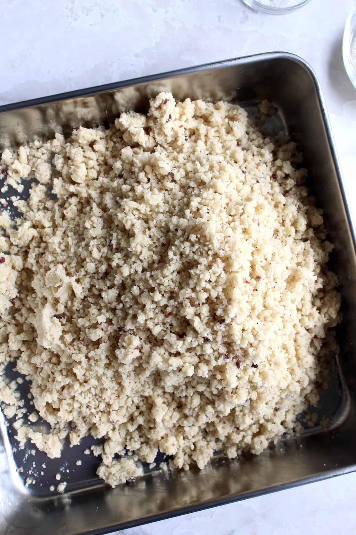 the shortbread dough is poured into a square stainless steel baking pan