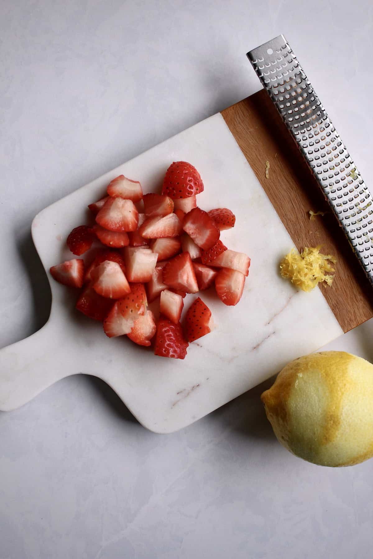 diced strawberries and lemon zest on a small cutting board