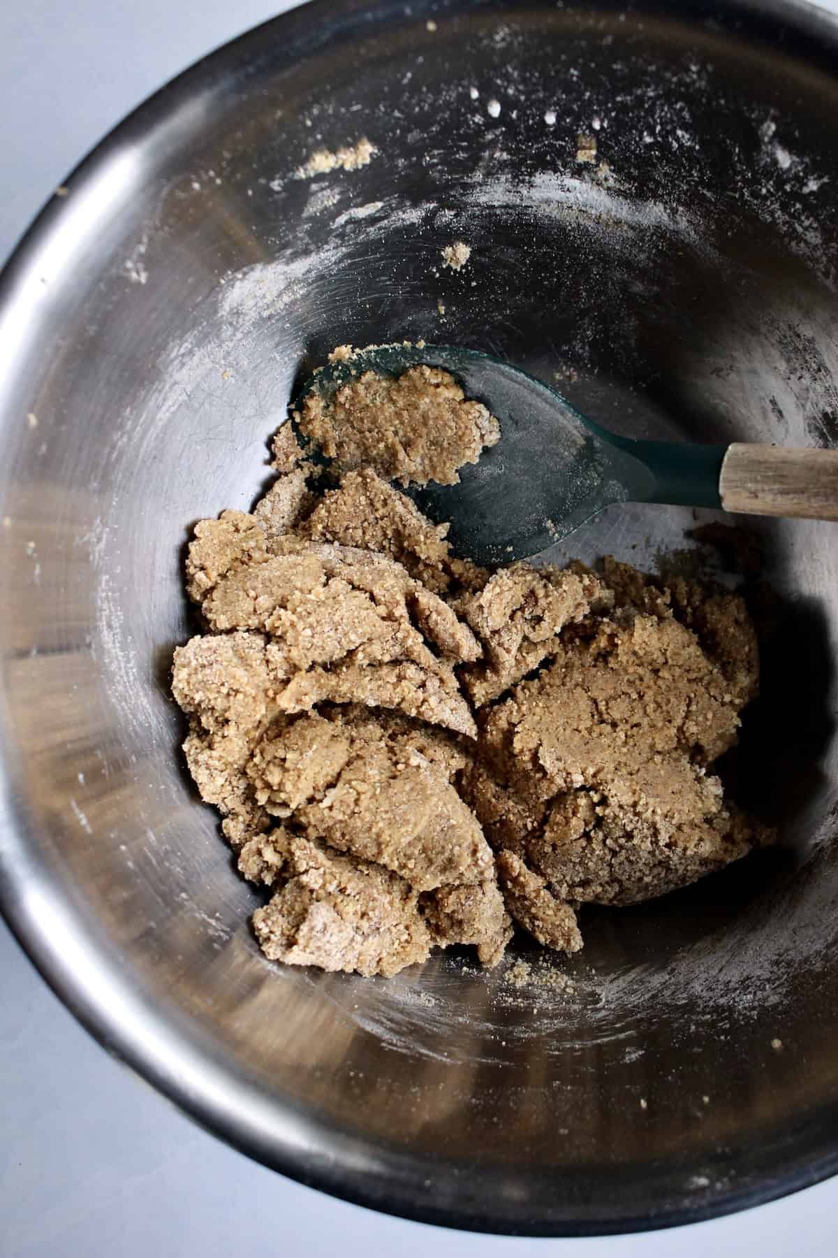 a wooden spoon is used to fold the cookie dough together.