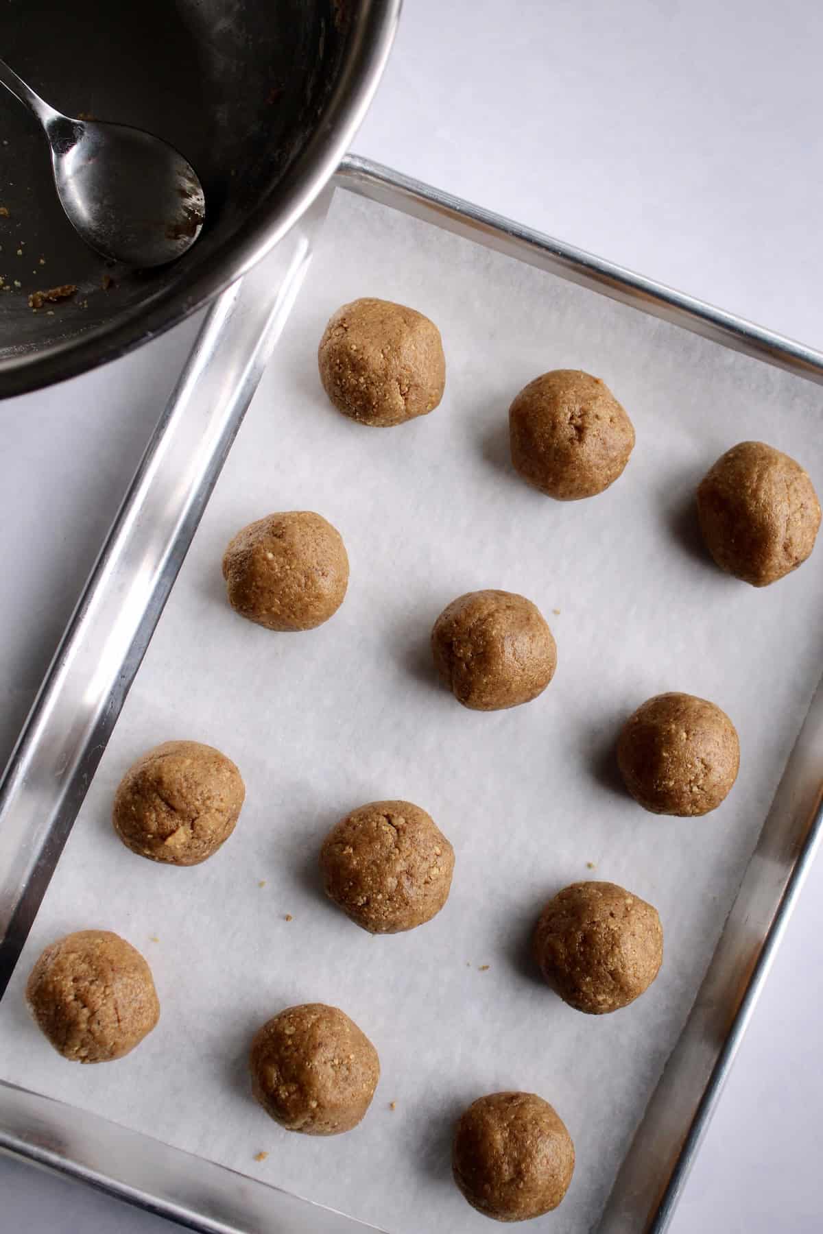 the cookie dough has been rolled into 12 large balls and arranged on a baking sheet.