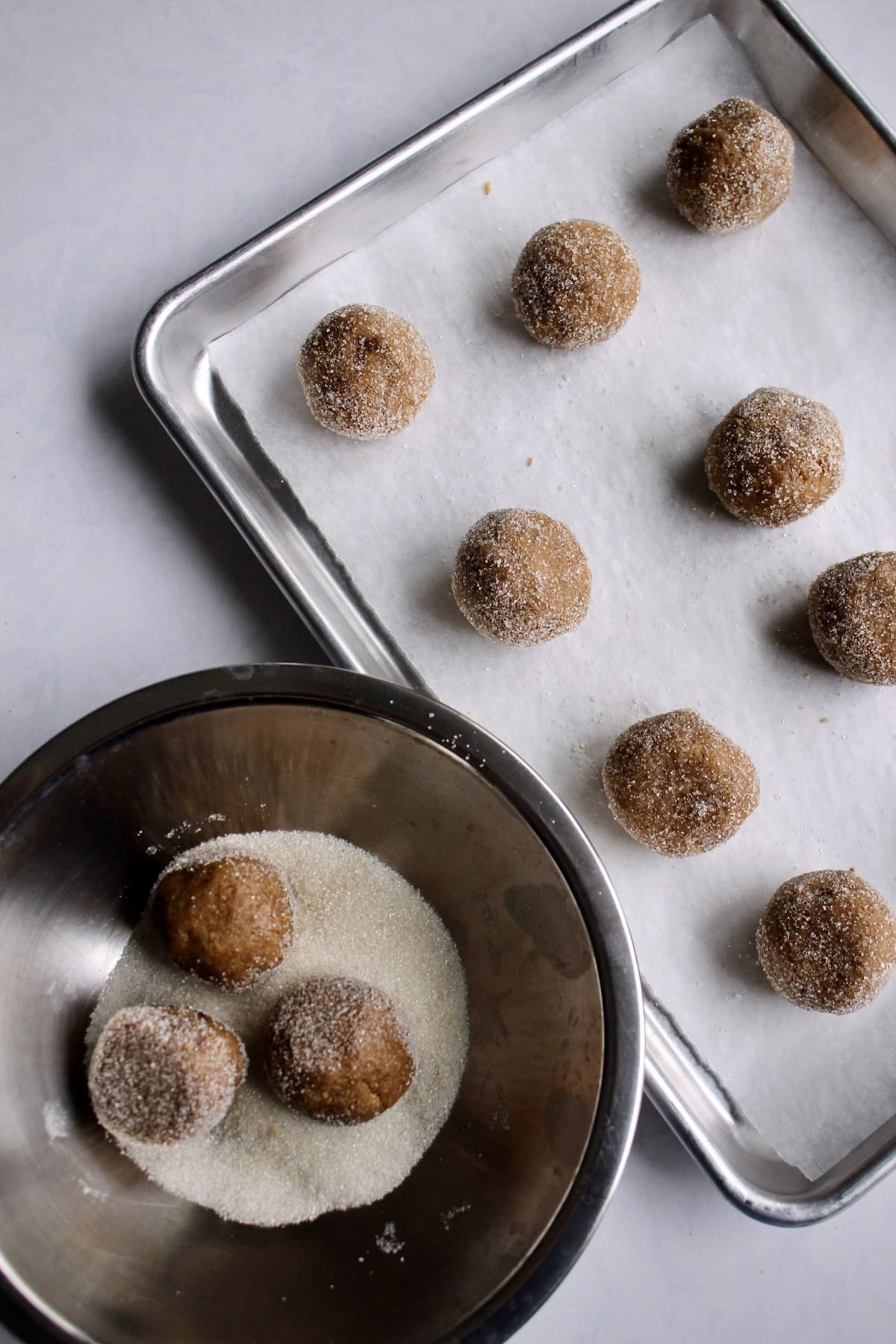 the chilled cookie dough balls are rolled in granulated sugar and arranged on baking sheets.