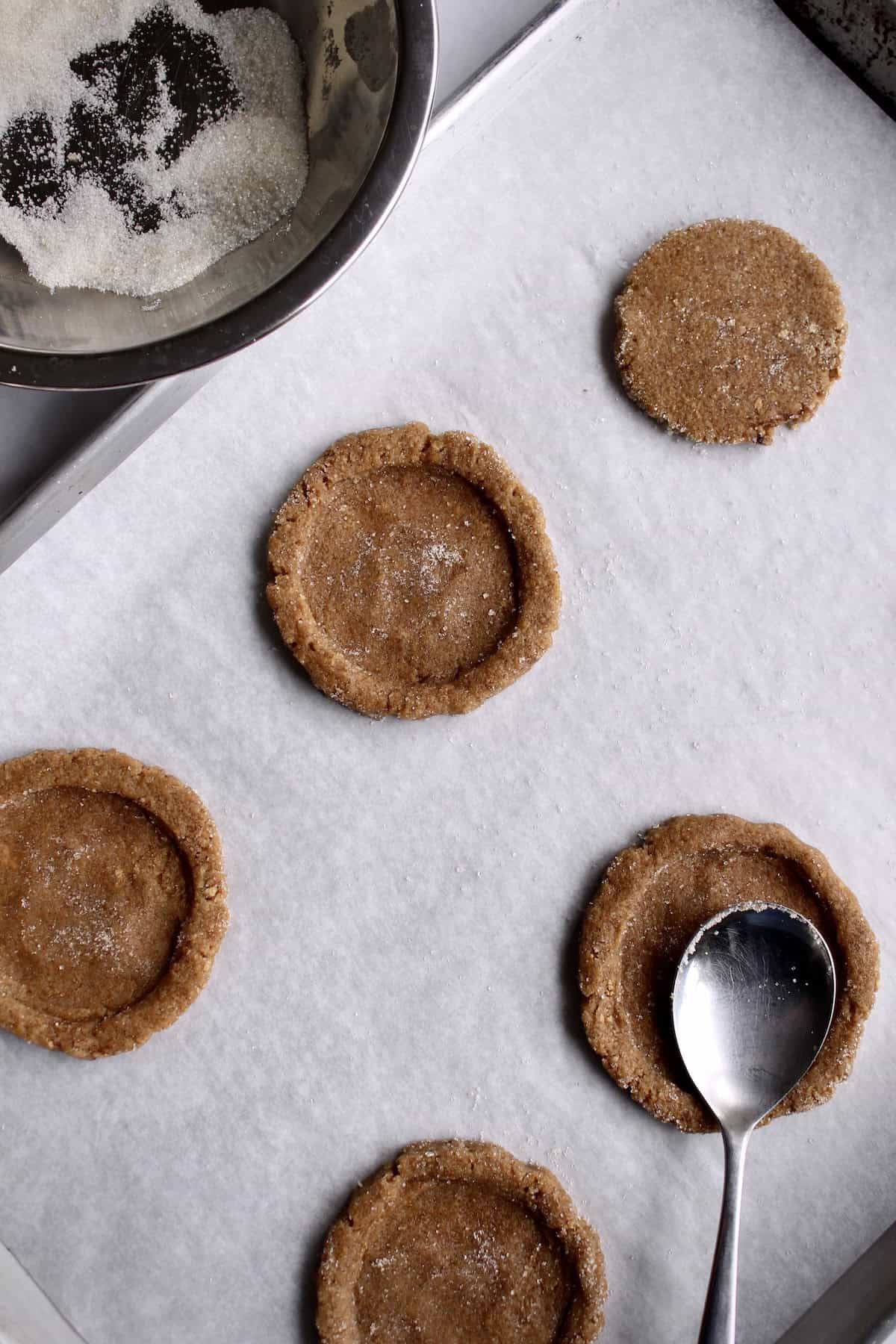 a broad soup spoon is pressed into the center of the cookie dough round, creating a shallow well.