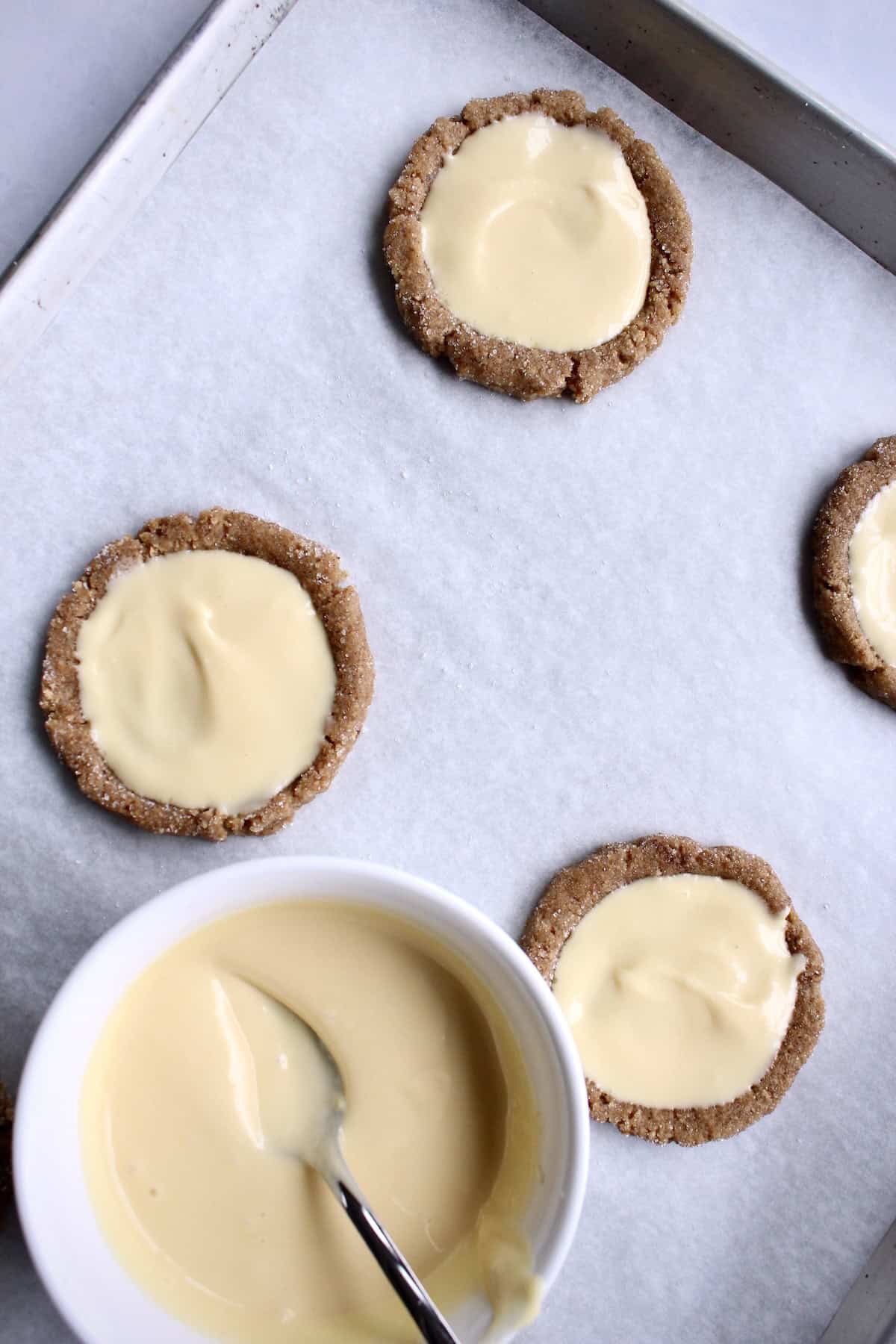 the prepared cheesecake filling is dolloped and smoothed into the center of each cookie dough well.