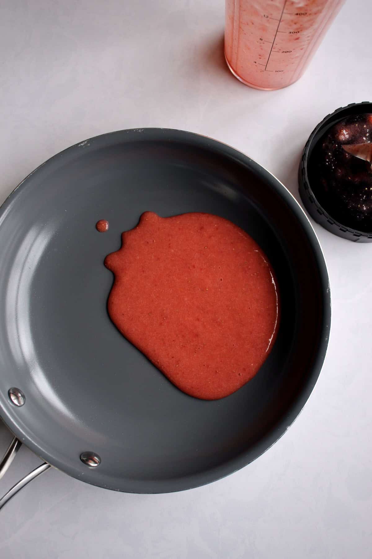 blended strawberry sauce is poured into a small saucepan.