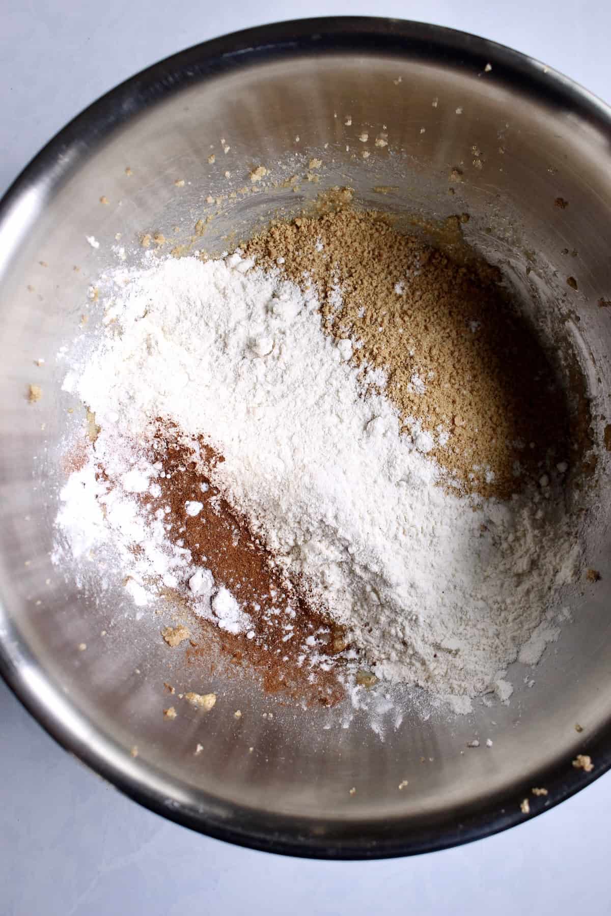 dry ingredients are sprinkled into the bowl with the butter and egg mixture.