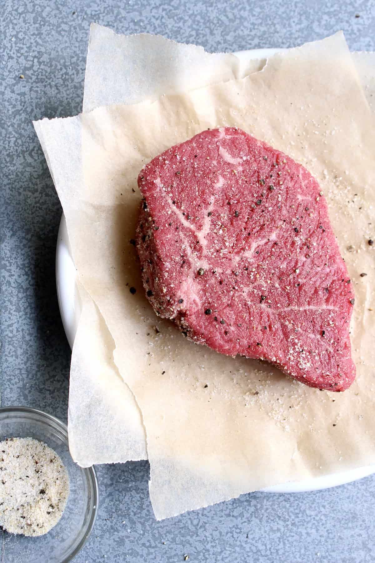 the spice mixture is sprinkled liberally over the surface of the raw steak
