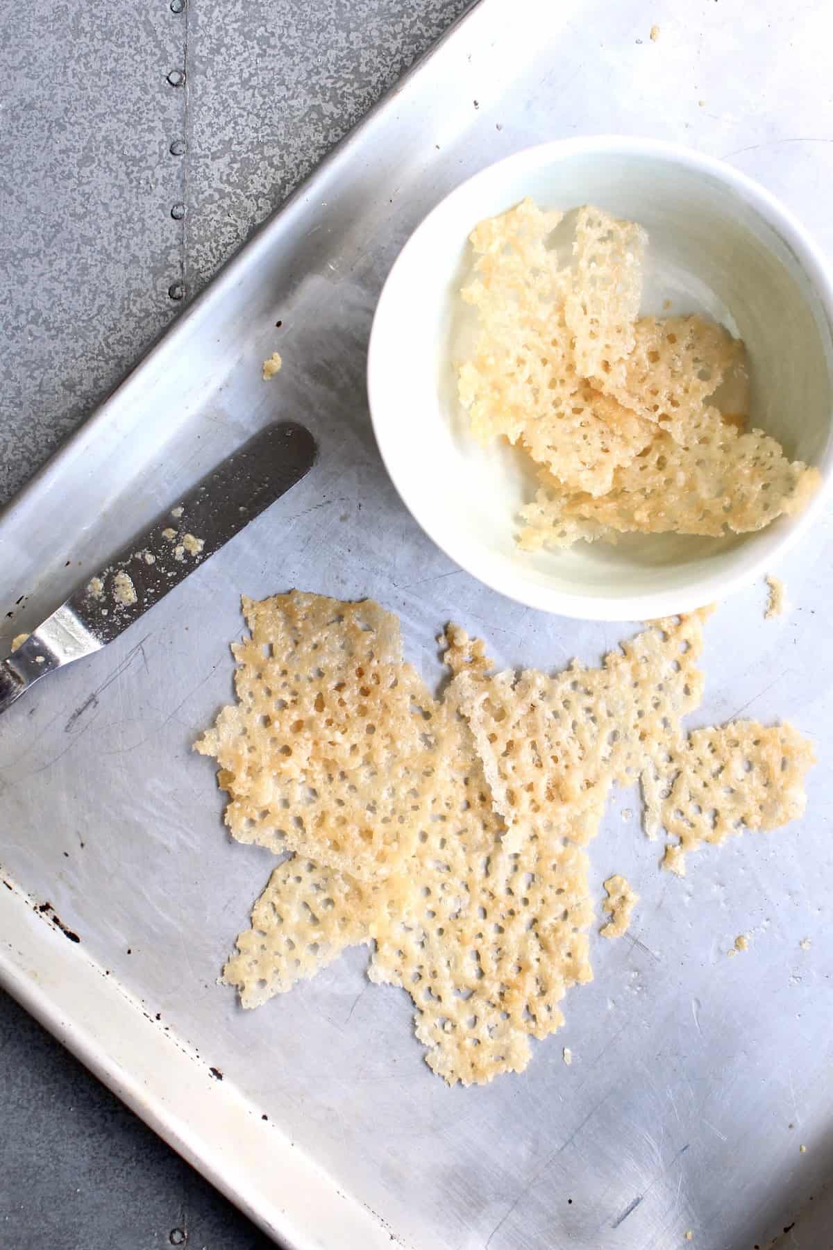 smaller shards of parmesan crisp are broken off the larger piece and transferred to a small bowl