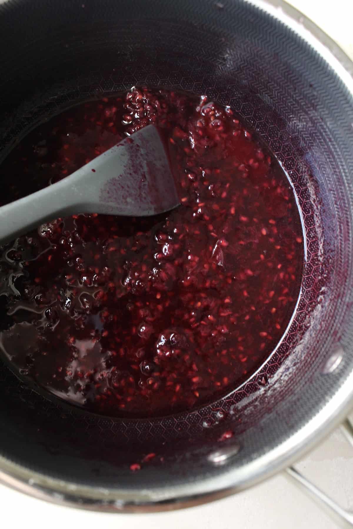 a small pot containing a deep purple berry sauce
