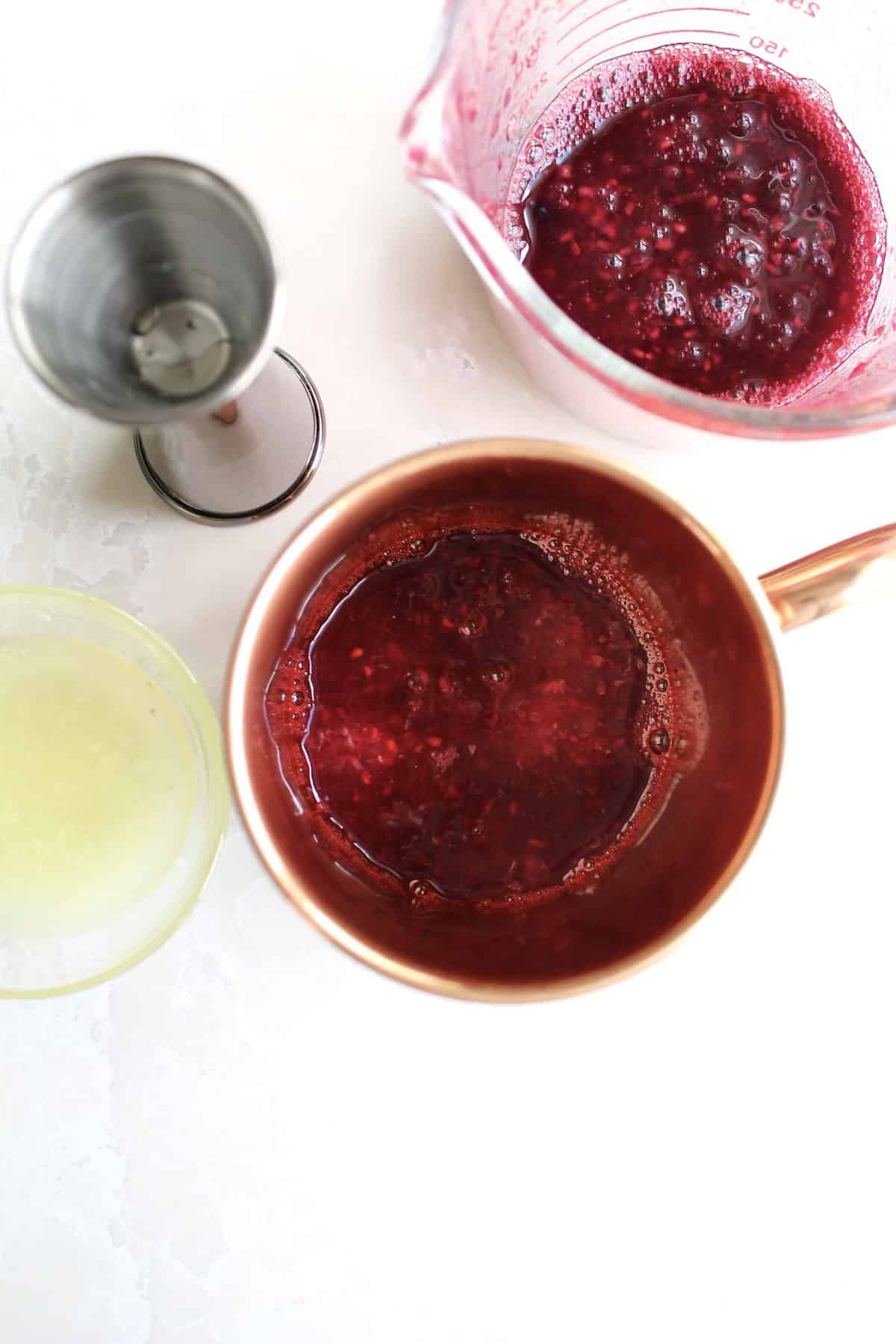 berry sauce and fresh lemon juice are poured into the bottom of a copper mug