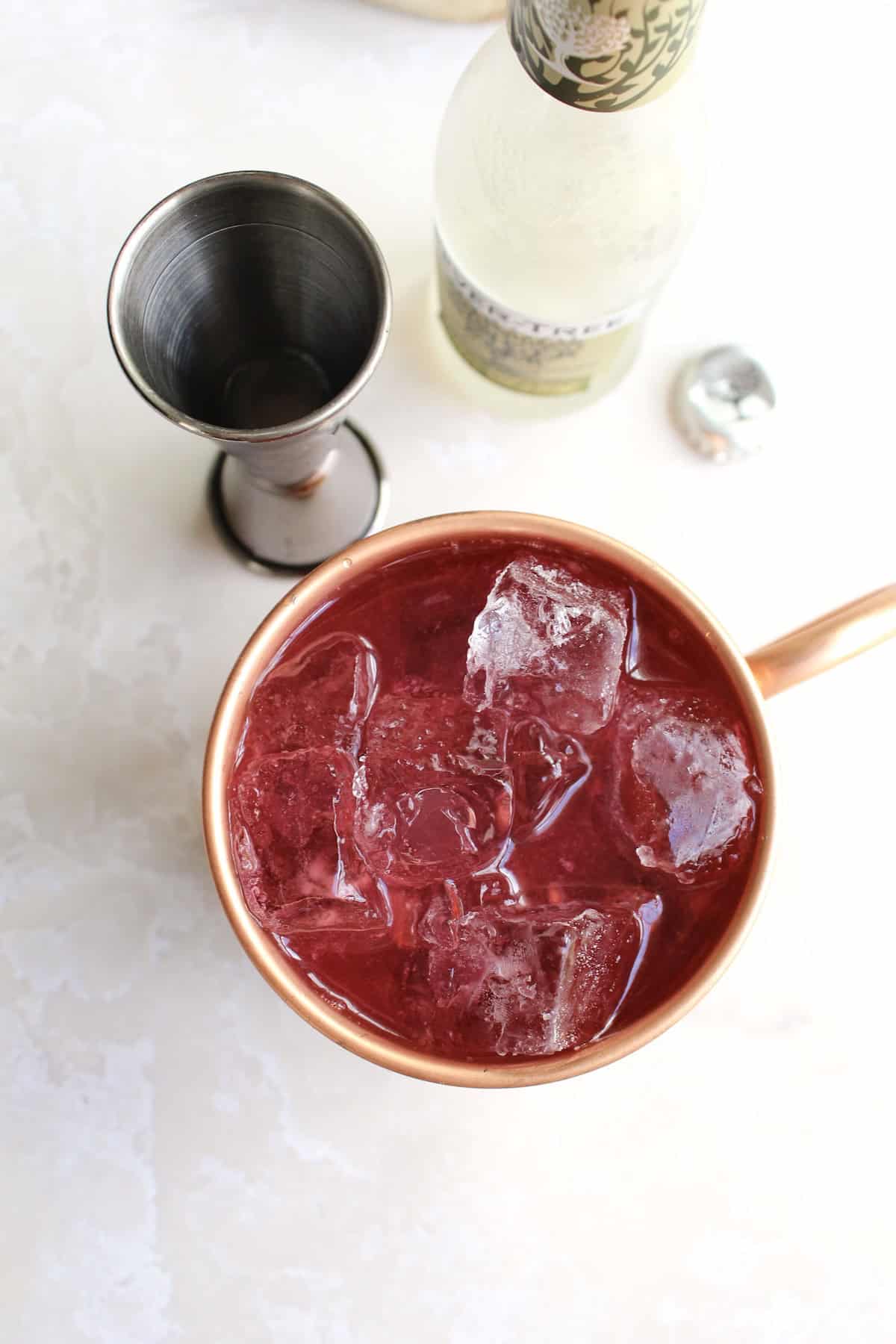 vodka and ginger beer are added to the mule mug, mixing with the berry sauce and turning the drink a vibrant fuchsia