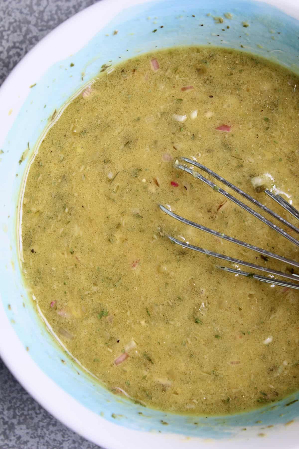 shallot lemon vinaigrette is whisked, creating a dressing that has a golden coloring with flecks of shallot and herbs