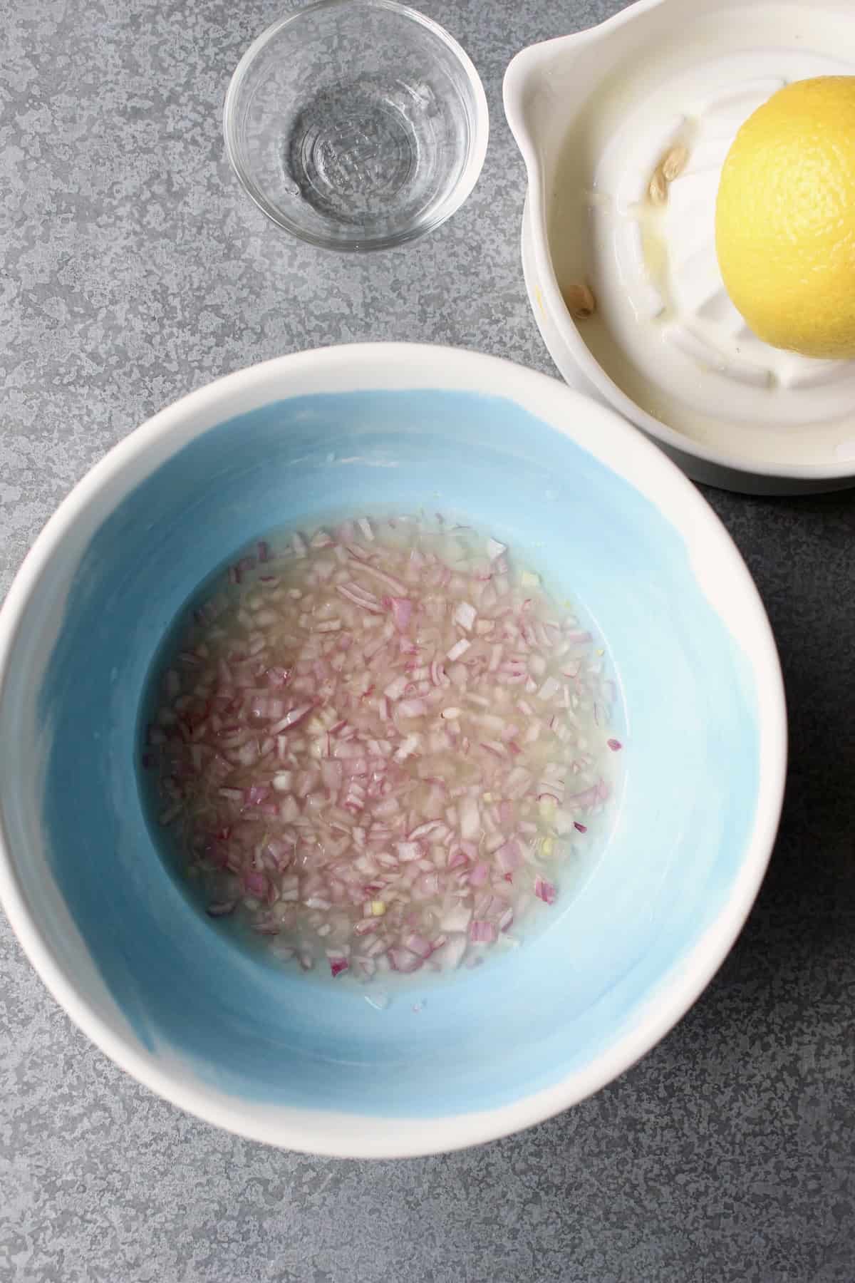 minced shallots and liquid ingredients are combined in a blue mixing bowl