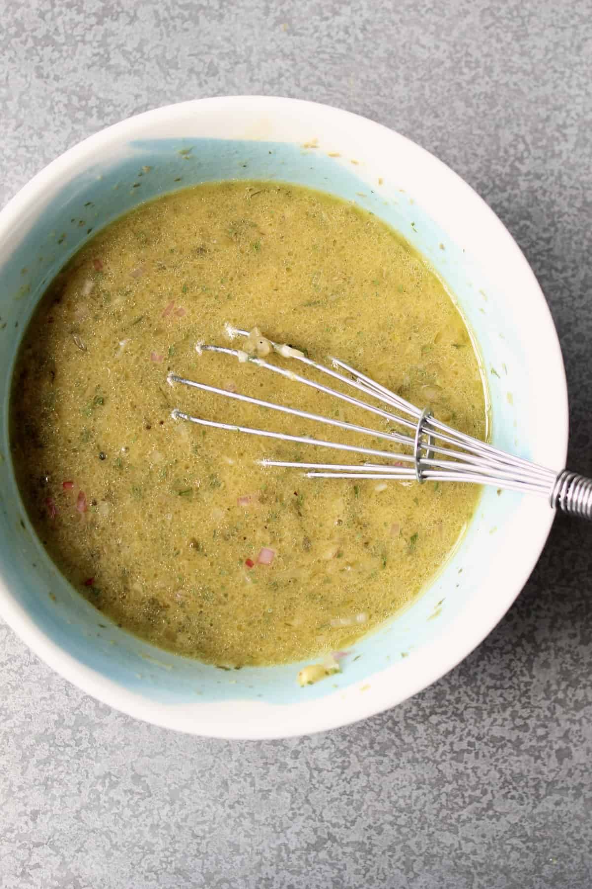 olive oil is whisked into the dressing, producing a yellow-gold vinaigrette that is flecked with bits of shallot, caper, and herbs.