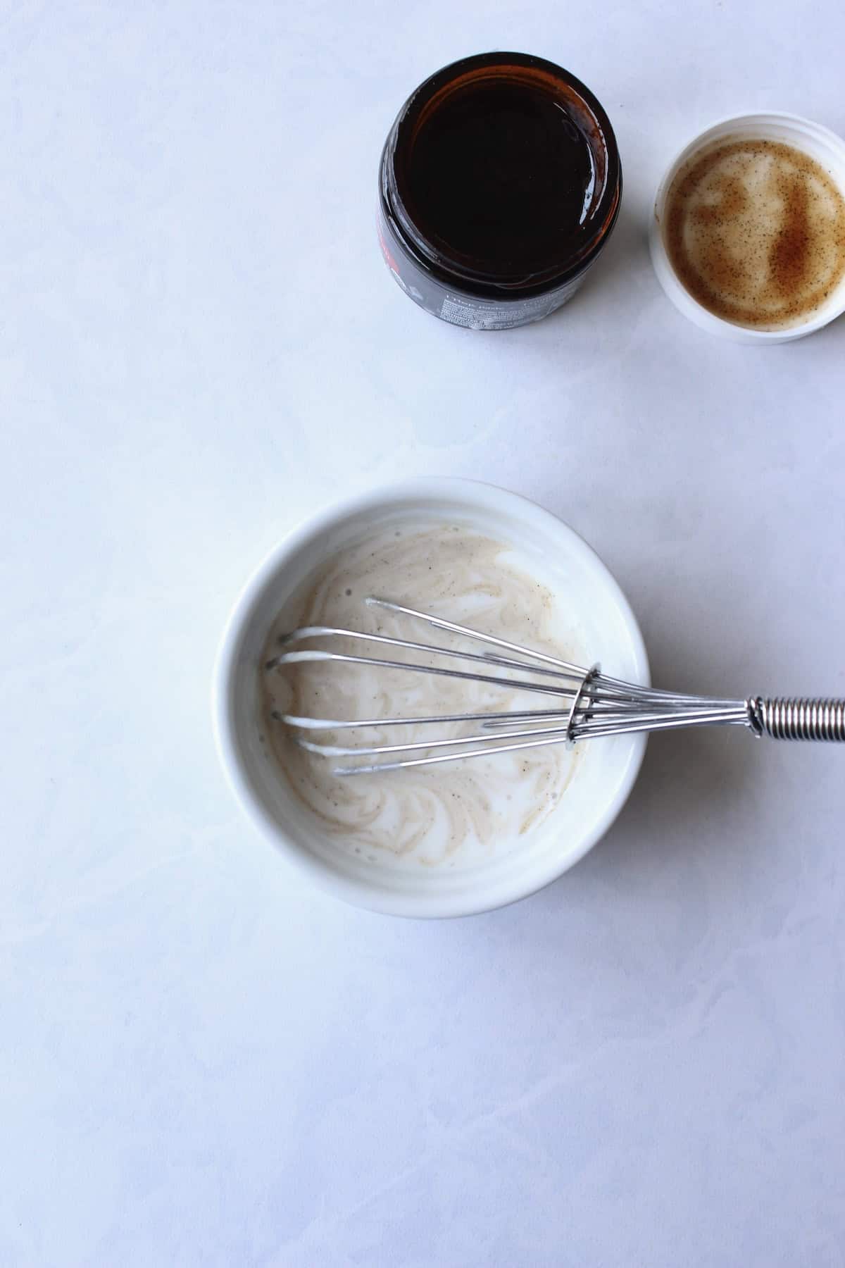 vanilla paste streaks through buttermilk as they are whisked together in a small bowl