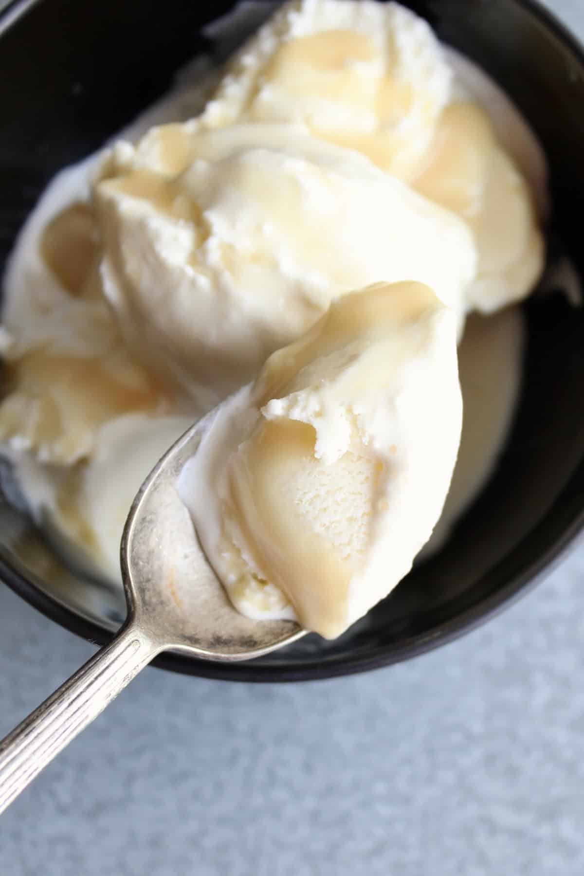 honey caramel sauce drizzled vanilla ice cream is spooned from a bowl