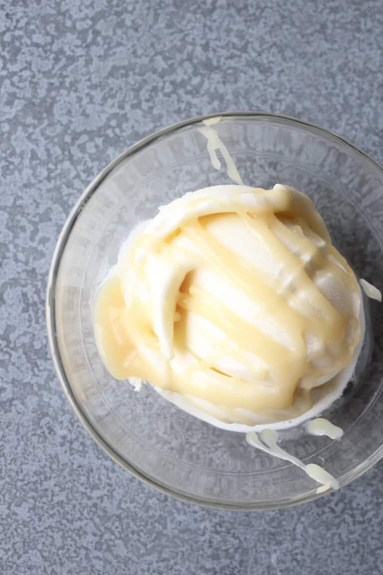 ribbons of honey caramel sauce are drizzled over a scoop of vanilla ice cream