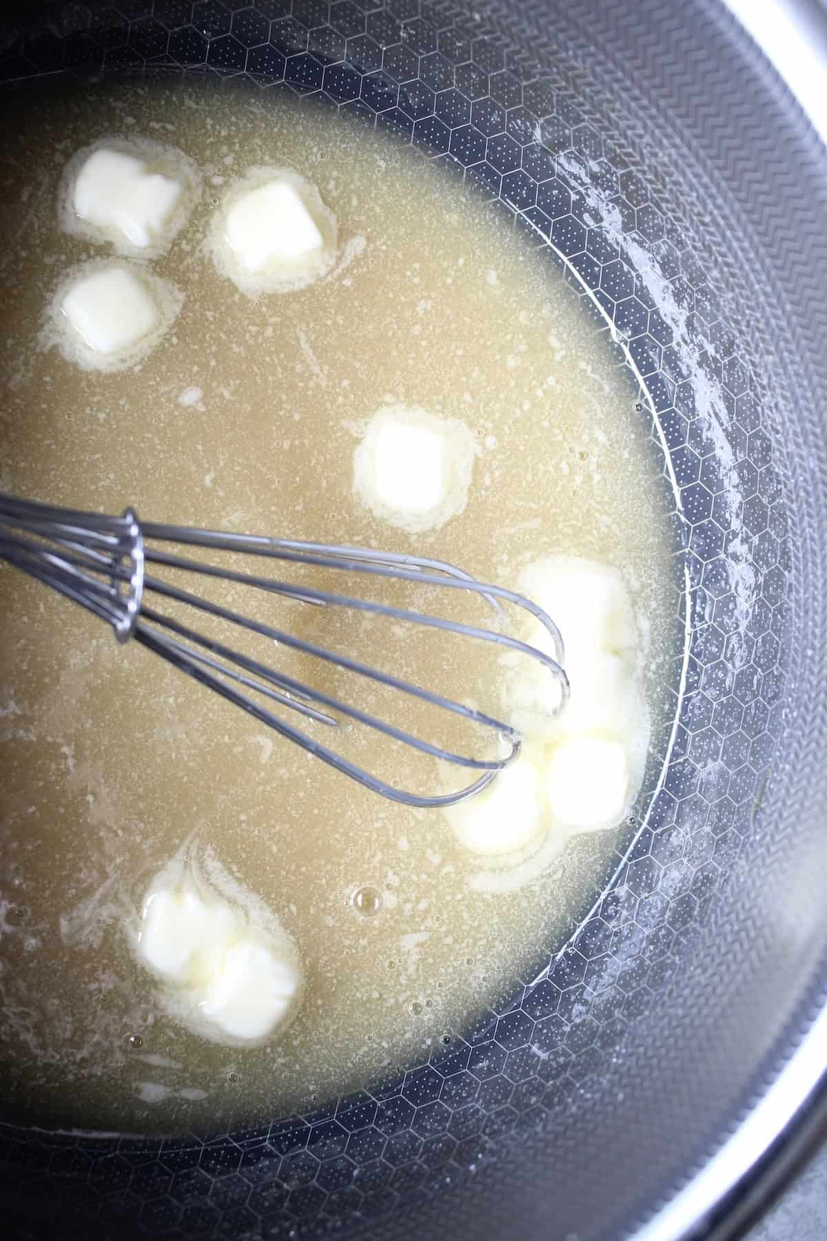 cubes of butter slowly melt as they swirl into in the caramel mixture