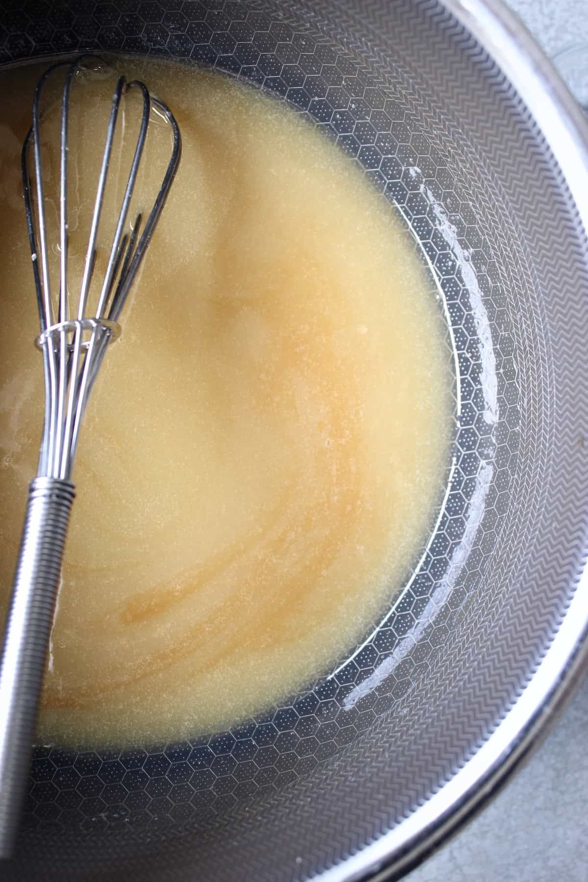 streaks of vanilla extract are visible as it is whisked into the shiny caramel sauce