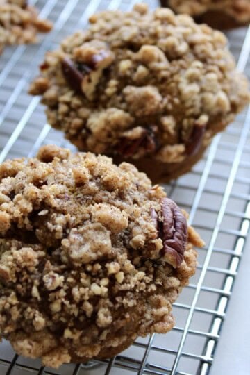pumpkin pecan streusel muffins lined up on a wire cooling rack