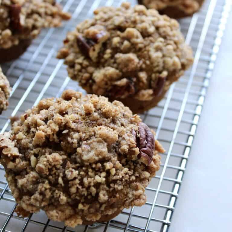 pumpkin pecan streusel muffins lined up on a wire cooling rack
