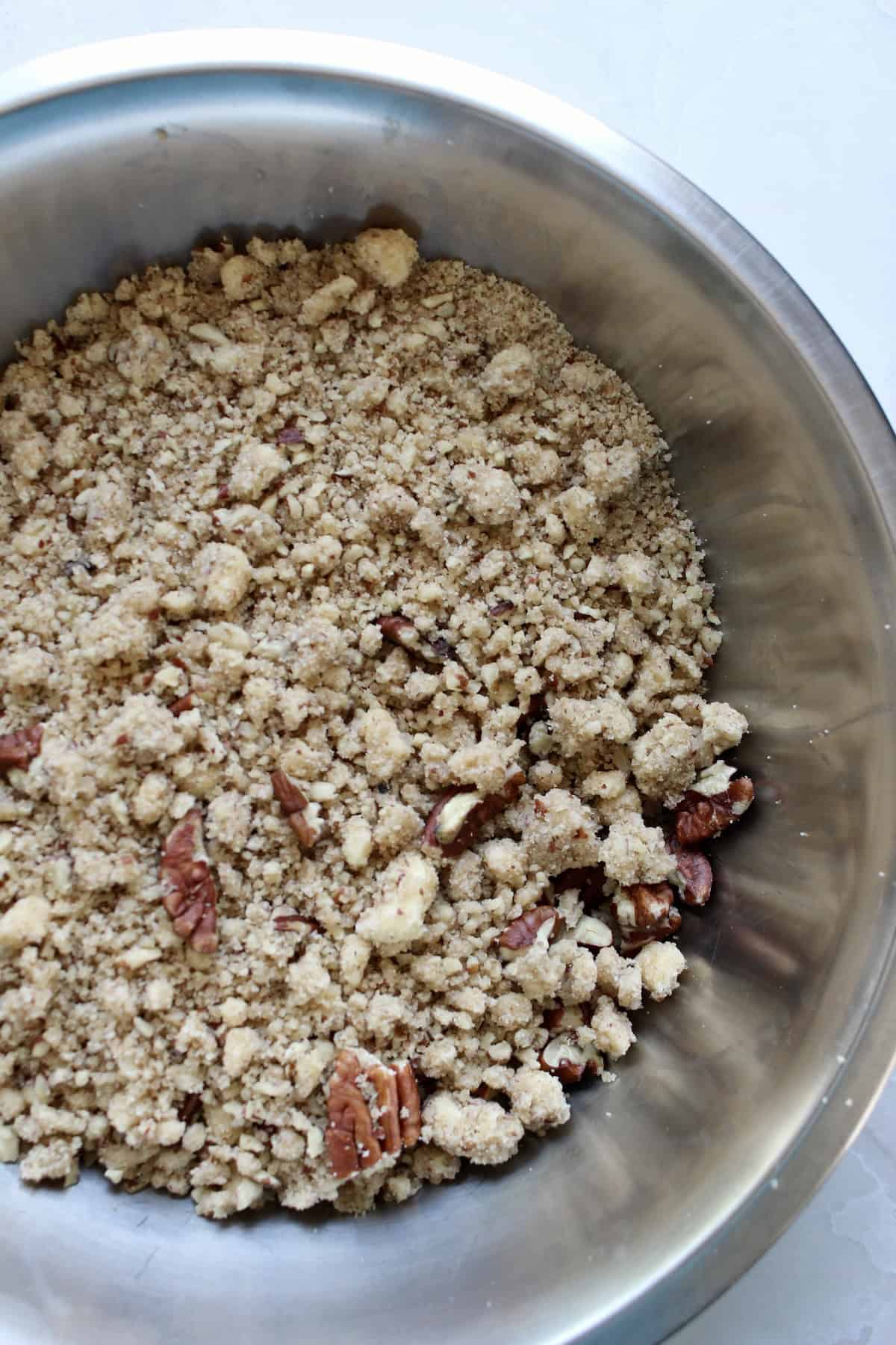 pecan streusel topping in a mixing bowl has a clumpy texture with prominent chunks of pecans