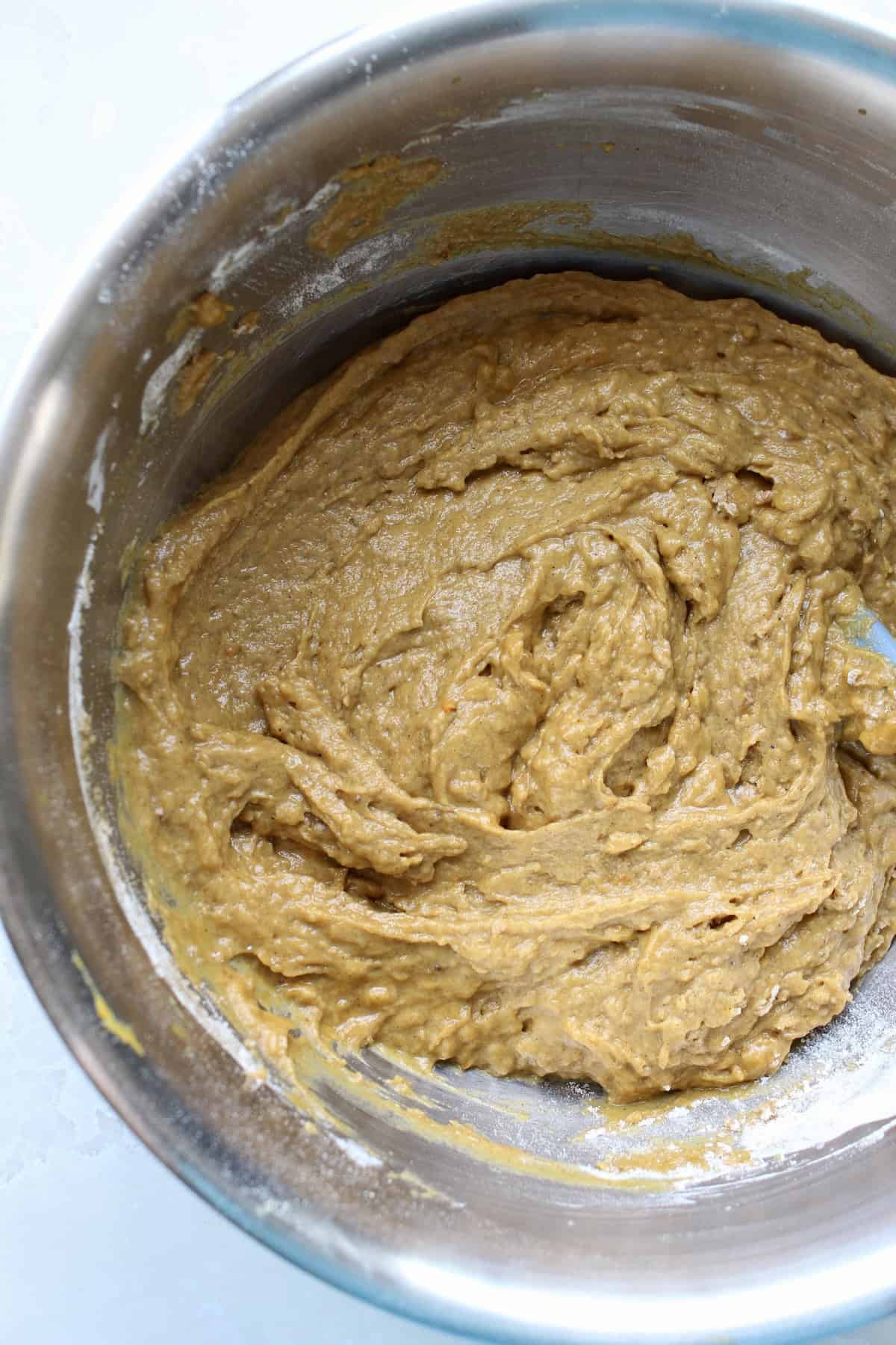 a large mixing bowl of pumpkin muffin batter has a thick, slightly lumpy texture