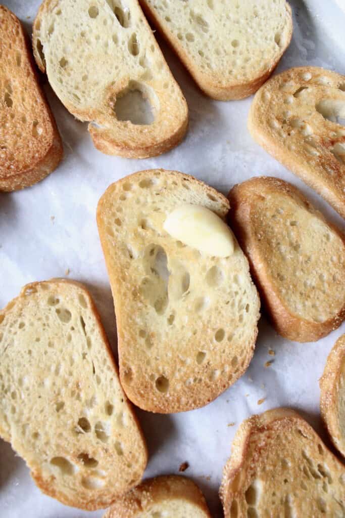 a whole garlic clove is rubbed on the surface of the bread slices.