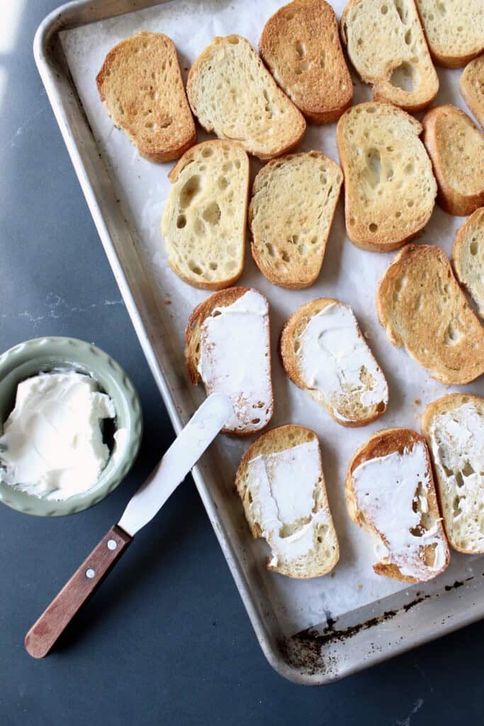 creamy goat cheese is applied to the surface of each piece of bread.